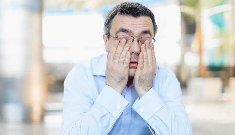 Hombre rascando sus ojos en señal de agotamiento