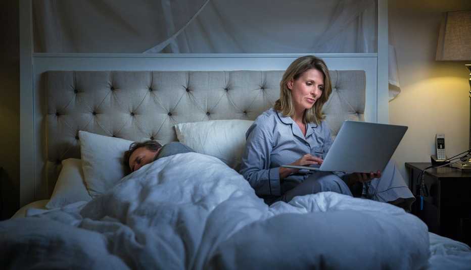 Mujer adulta utilizando un computador en la cama