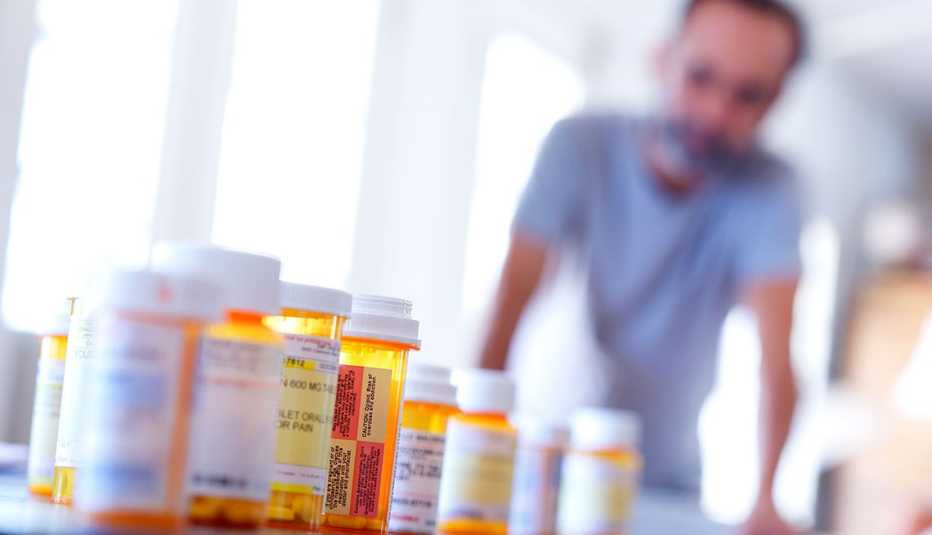 Hombre en el fondo y varios frascos de medicamentos en primer plano