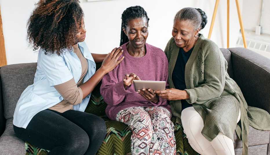 Tres mujeres sentadas en un sofá miran una tableta