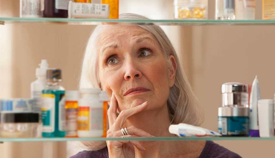 Una mujer mira su gabinete de medicamentos