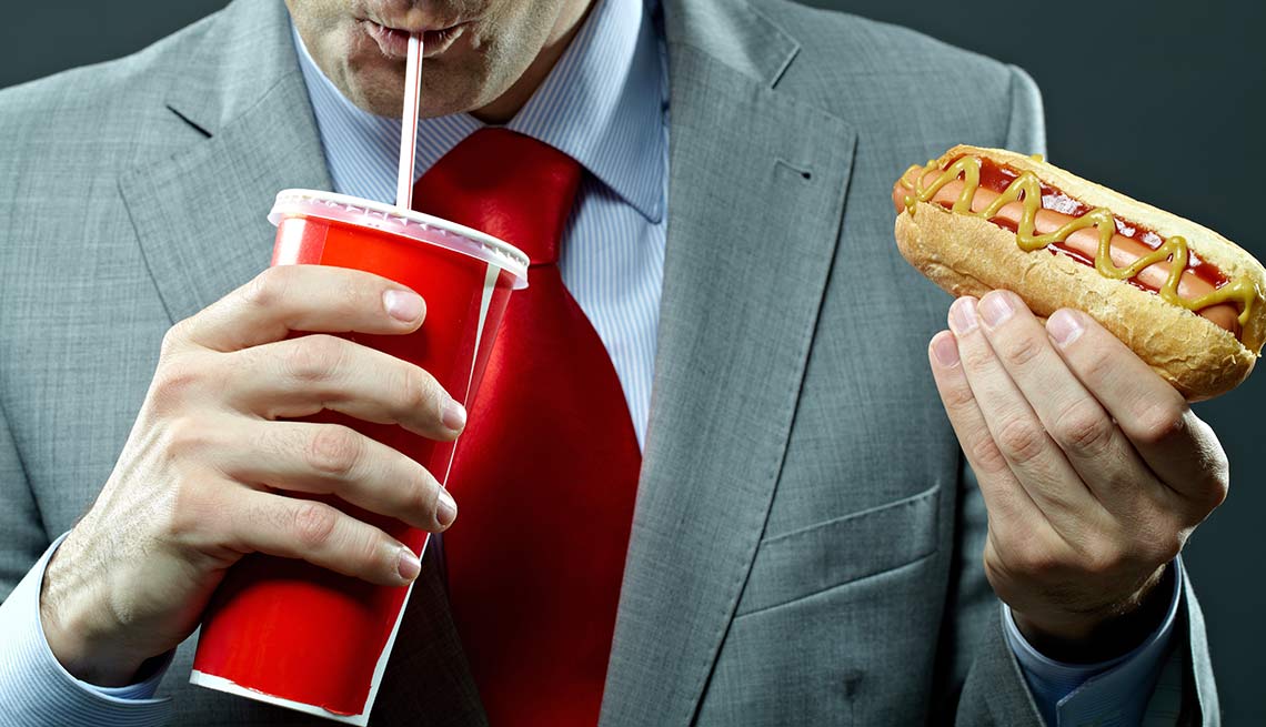 Hombre tomando soda y comiendo un hot dog
