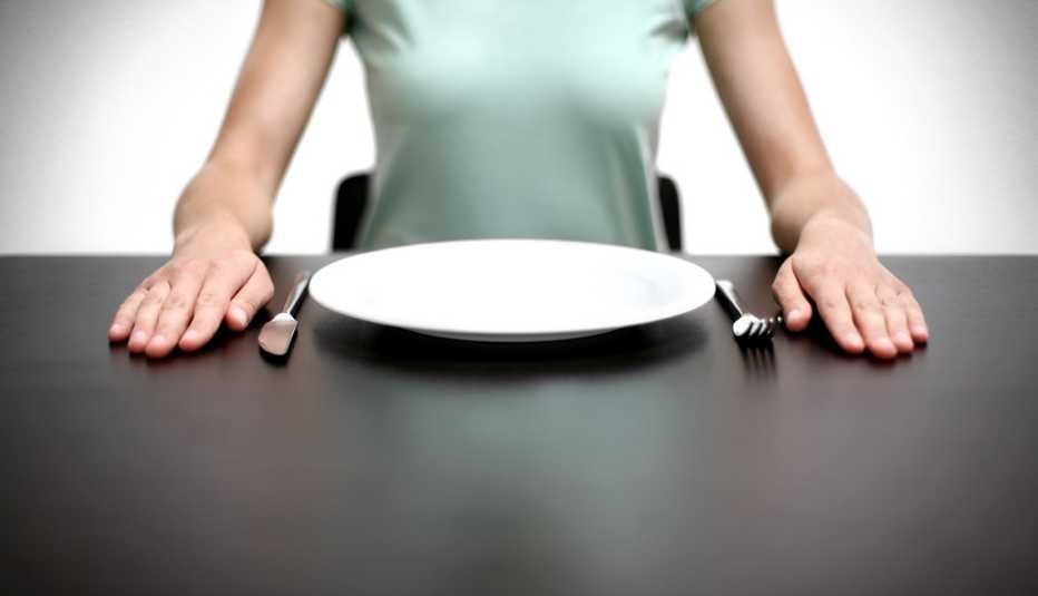 Mujer sentada frente a un plato vacio