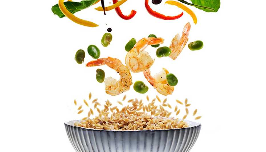 Camarones y vegetales cayendo a un plato hondo