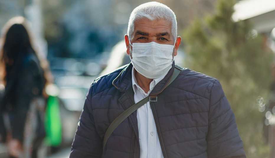 Un hombre usa una mascarilla mientras camina al aire libre