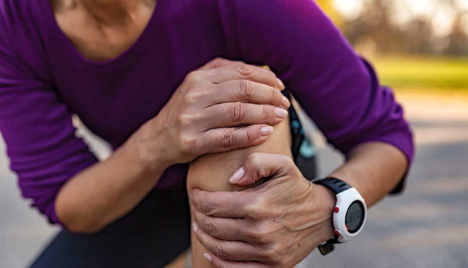 Una mujer abraza su rodilla en señal de dolor