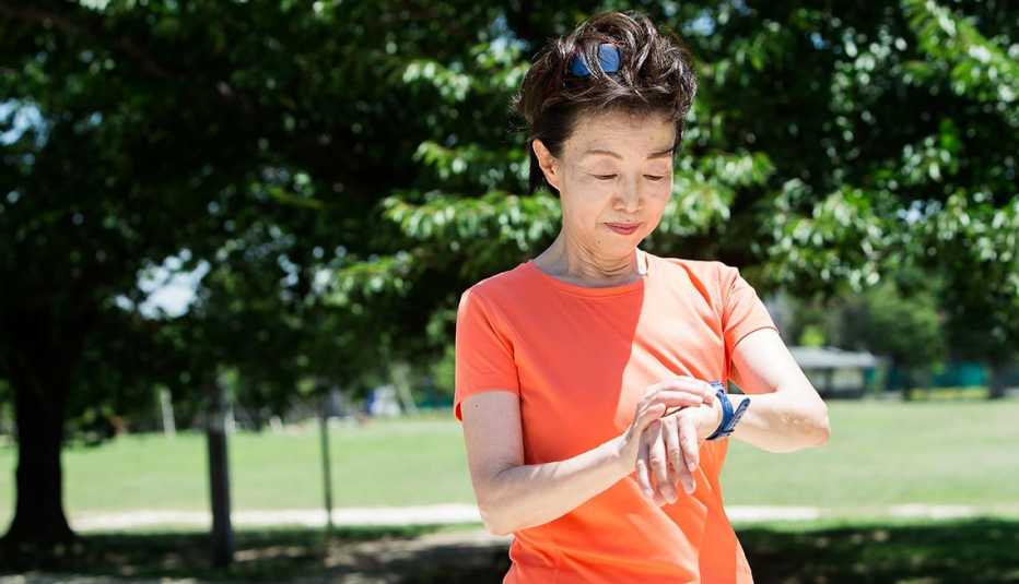 Una mujer mira su reloj mientras se ejercita al aire libre