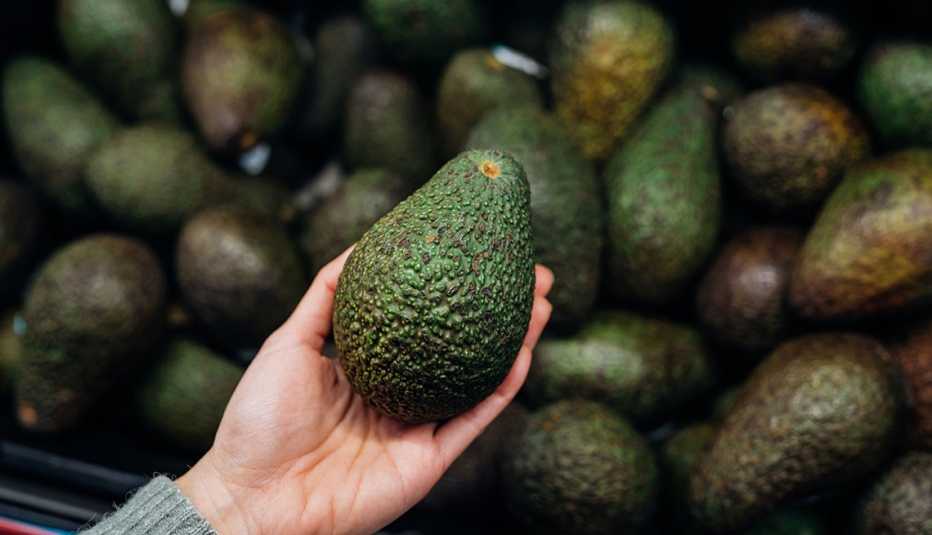 Una mujer comprando aguacates