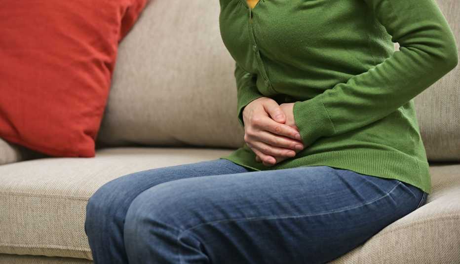 Una mujer se lleva las manos al vientre en señal de dolor