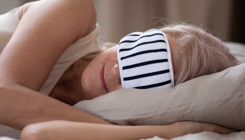 Mujer usando una máscara para dormir mientras duerme en un hotel