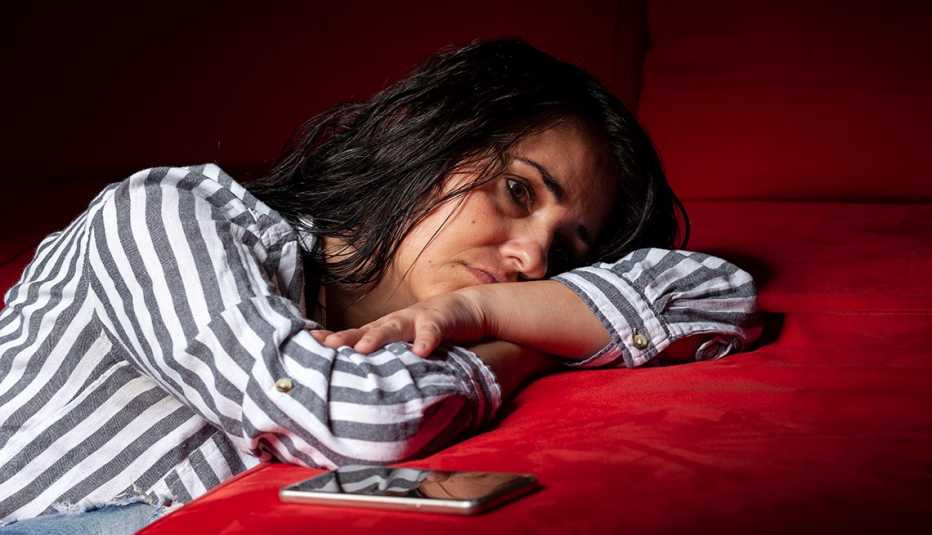 Una mujer triste y deprimida recostada de un sofá