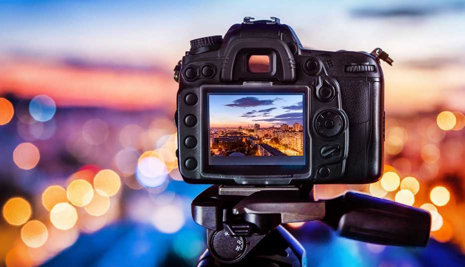 Cámara fotográfica sobre un trípode con luces de cuidad en el fondo