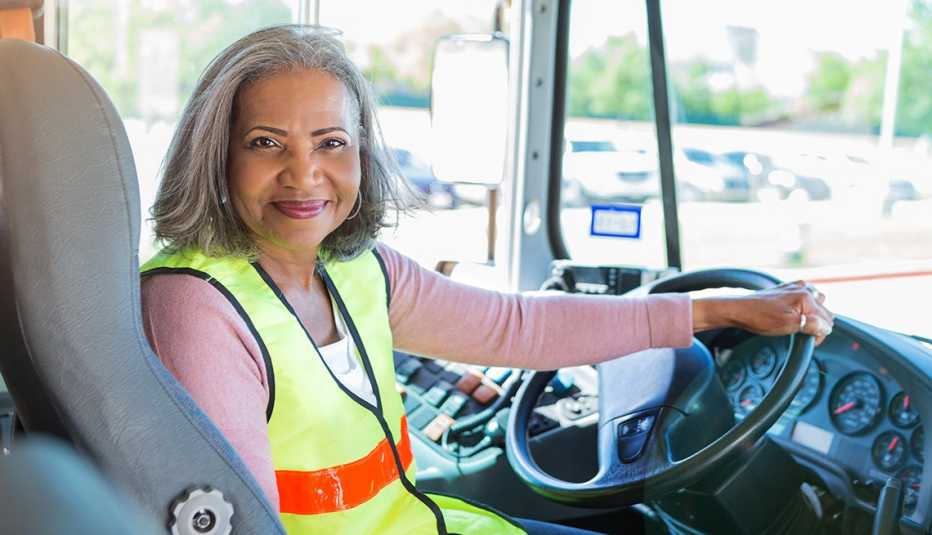 Mujer mayor manejando un bus escolar.