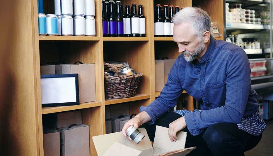 Hombre mayor empacando productos de un mueble.