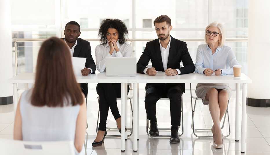 Dos hombres y dos mujeres entrevistan a una mujer en un panel 