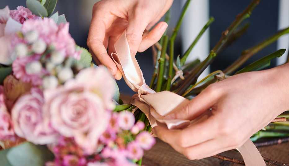 Manos de una mujer haciendo un arreglo de rosas rosadas