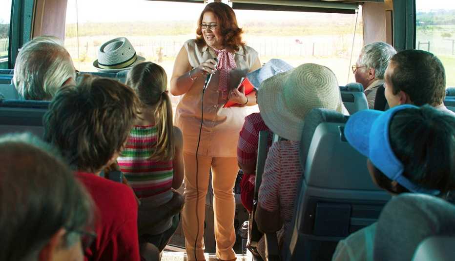 Guía turística hablando frente a un grupo de personas en un bus