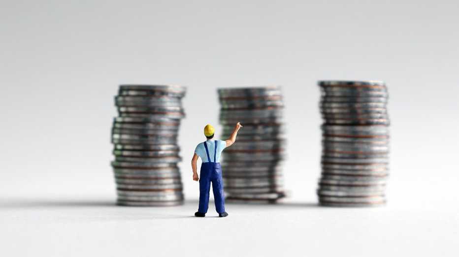 Imagen miniatura de un hombre frente a tres columnas de monedas apiladas