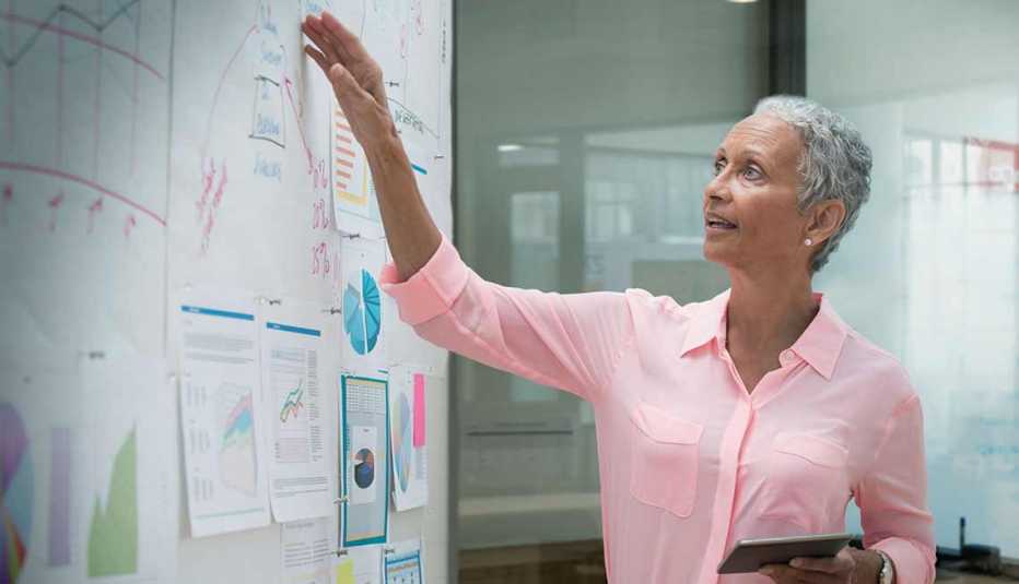 Mujer revisando proyecciones financieras sobre un tablero, trabajos con poco estrés, pero bien pagados