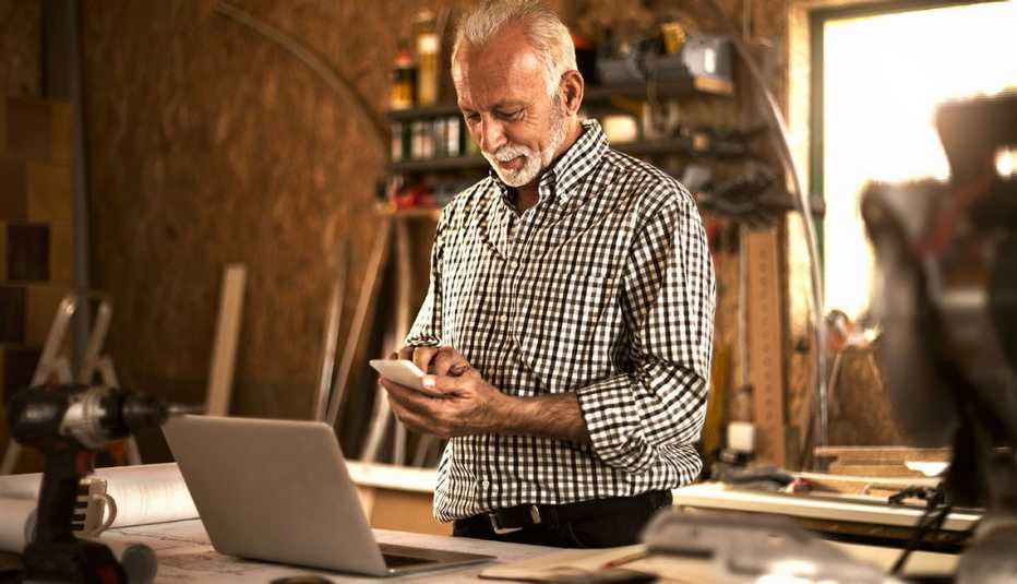 Hombre en su celular frente a su computador