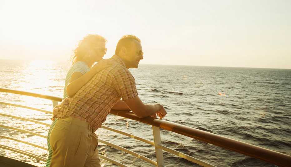Pareja mayor ve hacia el horizonte desde la cubierta de un barco.