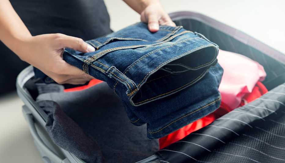 Mujer empaca ropa en una maleta de viaje.