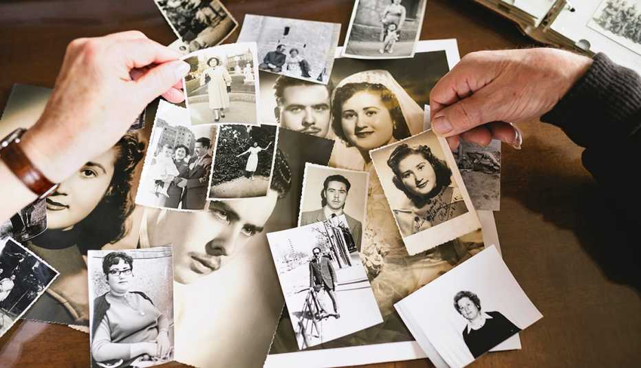 Dos manos sostienen fotos antiguas de retratos de personas