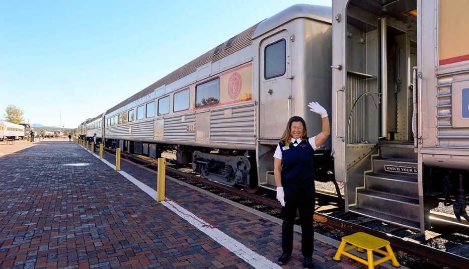 Empleada de una empresa de trenes aparece parada frente a un vagón estacionado