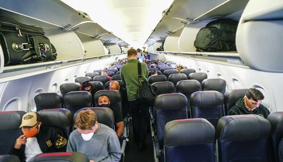 Persona camina por el pasillo central de un avión durante la pandemia de coronavirus