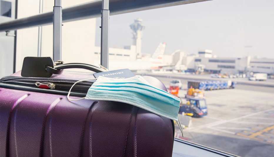 Pasaporte y mascarilla quirúrgica sobre una maleta