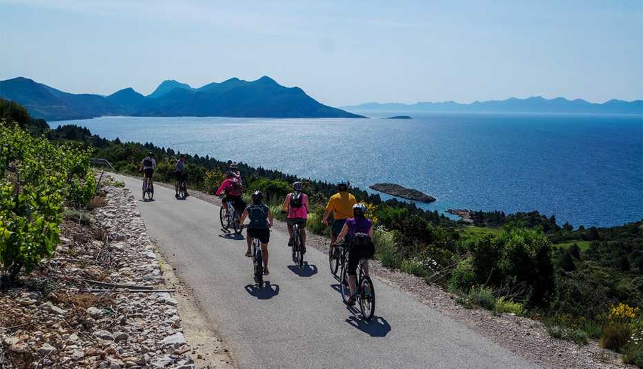 Grupo de personas en bicicleta por una carretera costera