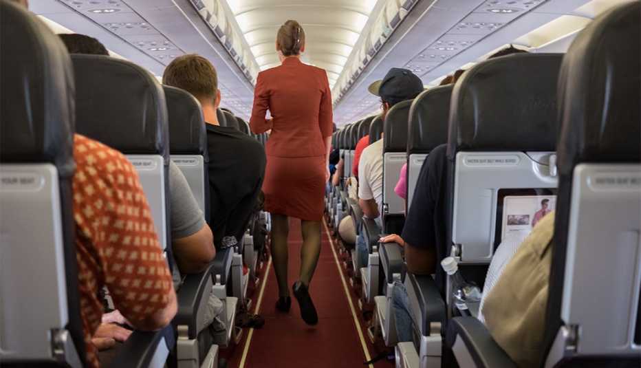 Azafata camina por el pasillo de un avión