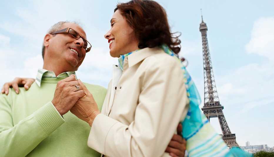 una pareja abrazándose con la Torre Eiffel al fondo