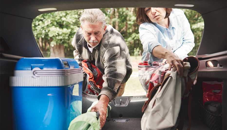 Pareja cargando el auto con suministros para acampar