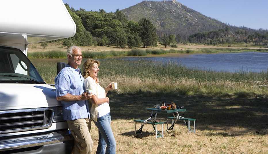 Pareja observa un paisaje montañoso en frente de su casas rodantes 