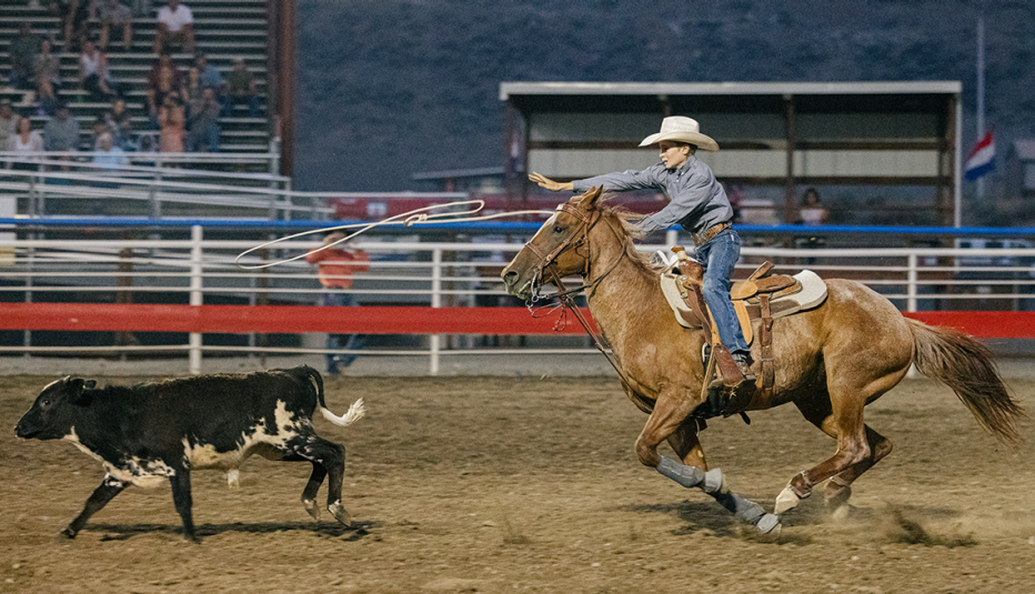 Hombre que monta a caballo y persigue una vaca
