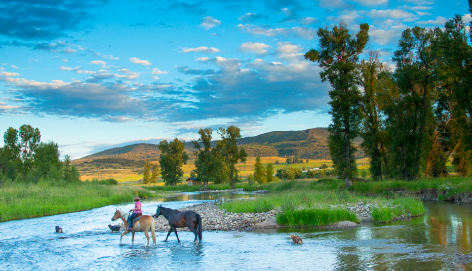 Persona pasa un río a caballo
