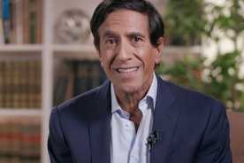 Sanjay Gupta, M.D. smiling in front of a bookshelf