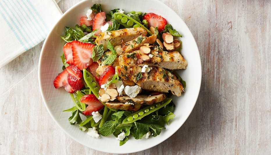 A close-up view of a strawberry chicken salad with mint and goat cheese in a bowl