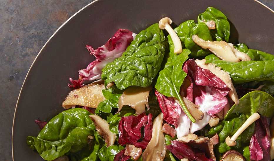 A close-up view of spinach and warm mushroom salad in a pan