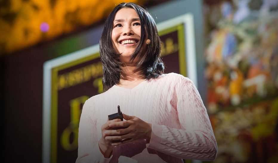 A woman, Lisa Bu, speaking on stage at a TED event