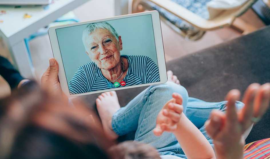 A family having a video call with a woman on their tablet